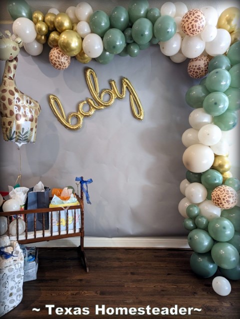 Baby Shower Photo op με θαλασσινά πράσινα και χρυσά μπαλόνια, καμηλοπάρδαλη μπαλούν, μωρό διακόσμηση και Jenny Lind Cradle για να κρατήσει δώρα. #Texashomesteader